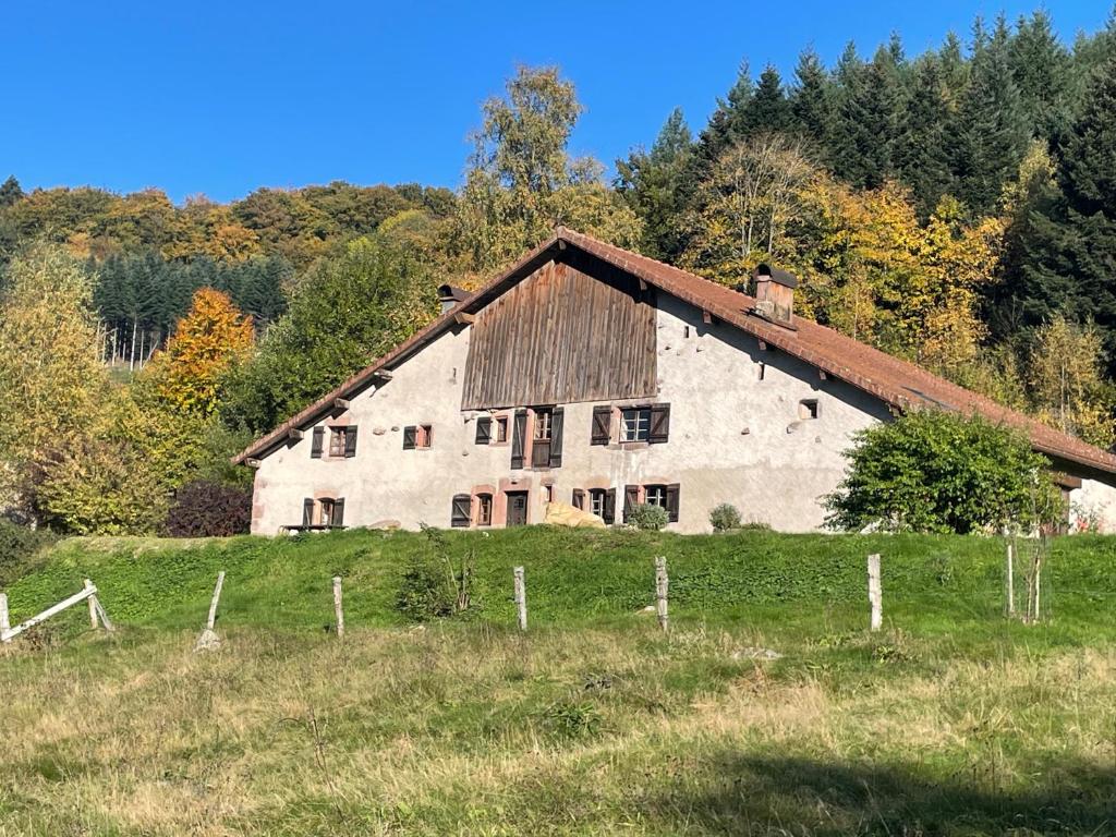a large white barn in a field with trees at La Hutte in Tendon