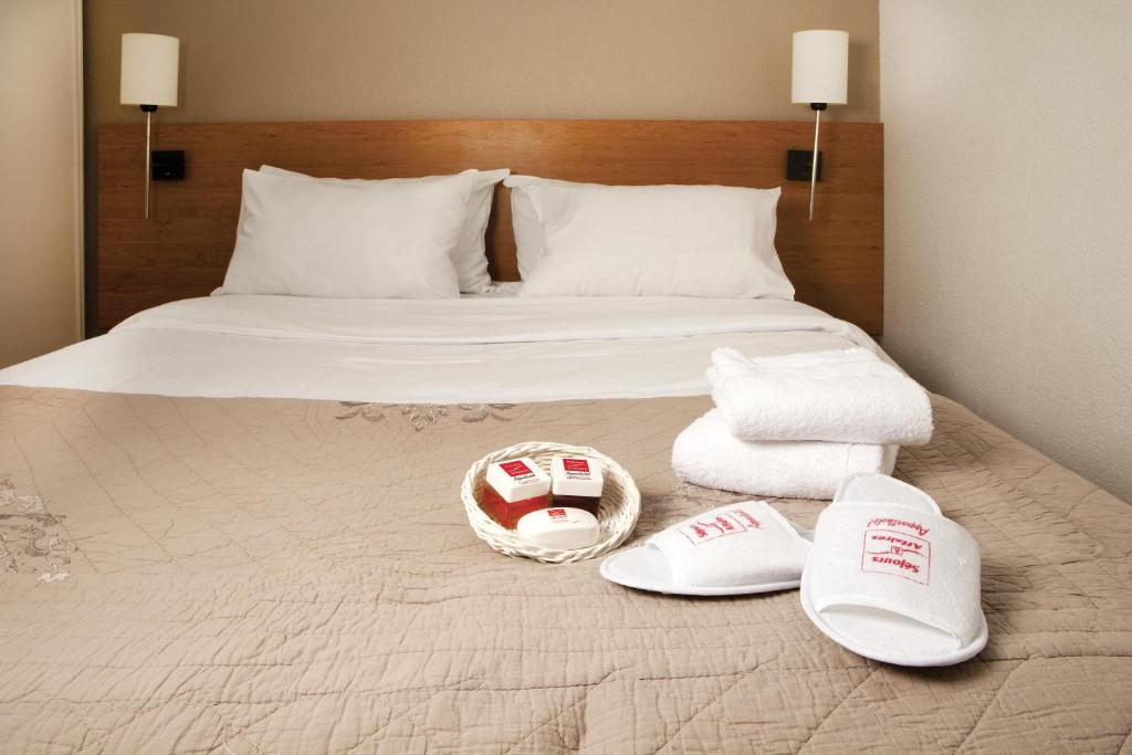 a bed with two towels and a pair of shoes on it at Séjours & Affaires Pantin Charles De Gaulle in Pantin