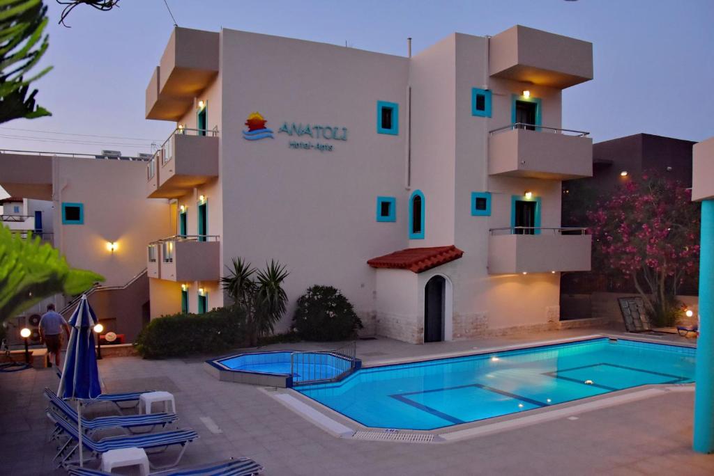 un hôtel avec une piscine en face d'un bâtiment dans l'établissement Hotel Anatoli Apartments, à Stalida