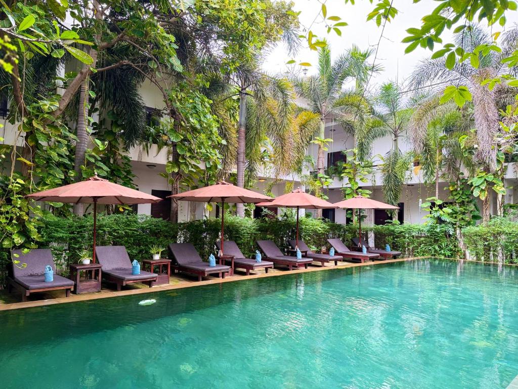 ein Hotelpool mit Liegen und Sonnenschirmen in der Unterkunft The Moon Residence & Spa in Siem Reap