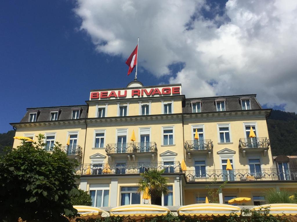 a large building with a flag on top of it at Romantik Hotel Beau Rivage Weggis - Beau Rivage Collection in Weggis