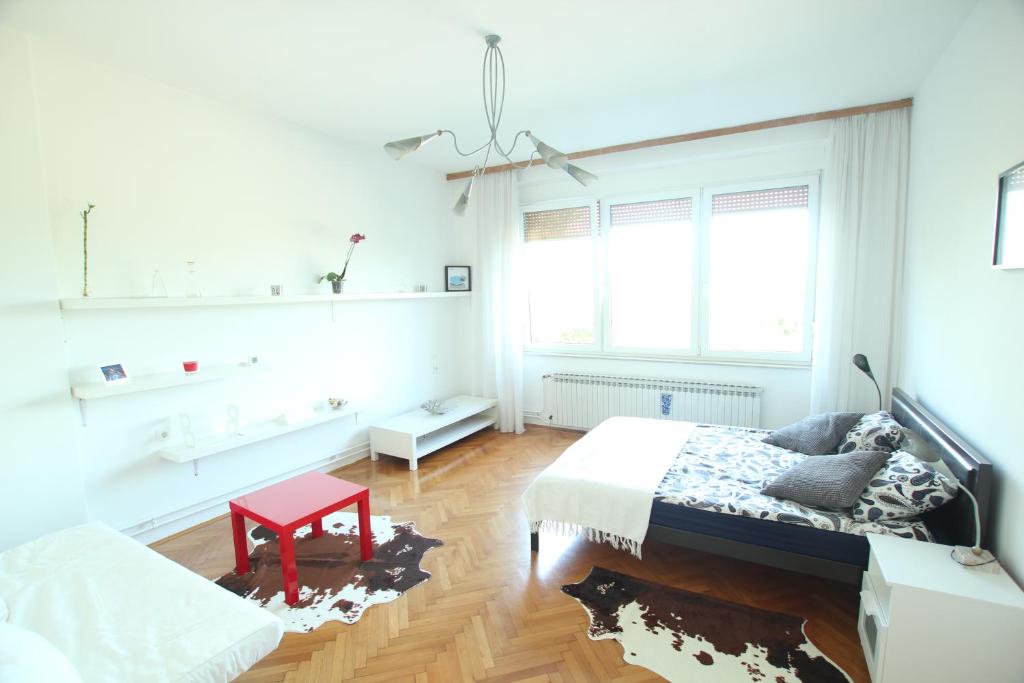 a white bedroom with a bed and a red table at Apartment Keglich in Zagreb