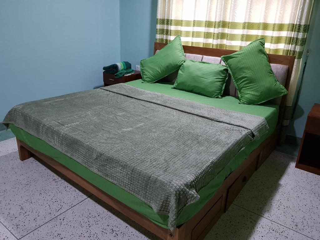 a bed with green pillows in a room at Seethevi Hotels in Batticaloa