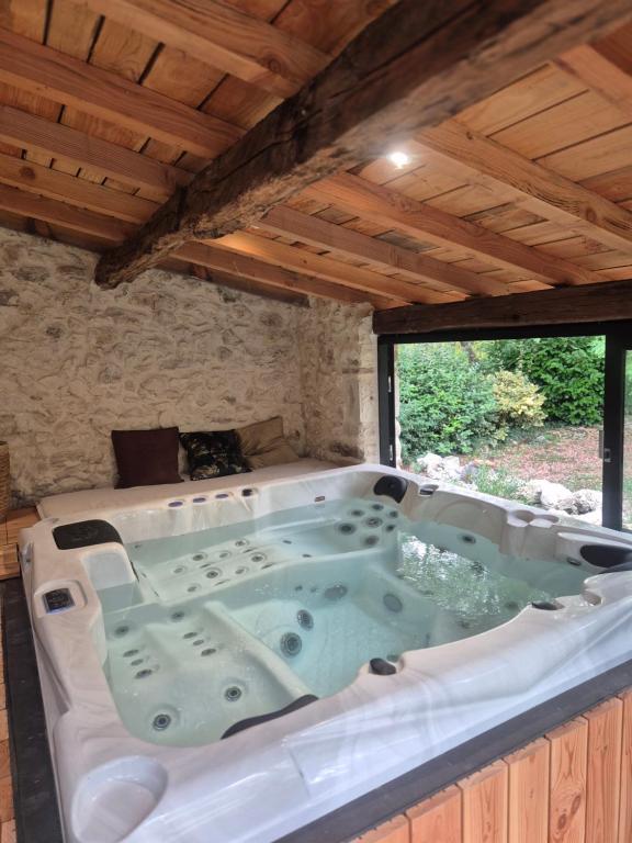 a large bath tub in a room with a window at La Maison Or Azur- Spa Jacuzzi- Terrasse - Vue Nature in Penne-dʼAgenais