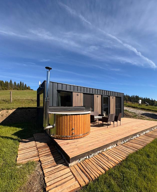 ein kleines Haus auf einer Holzterrasse auf einem Feld in der Unterkunft Orava Valley in Jasenica