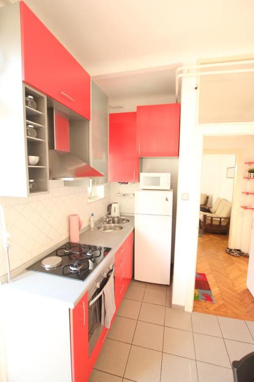 kuchnia z czerwonymi szafkami i białą lodówką w obiekcie Apartment Keglich w Zagrzebiu