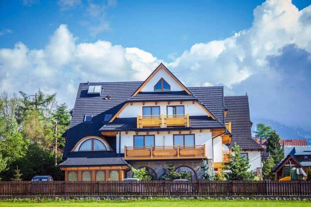 una gran casa blanca con techo de gambrel en Sichlański Dworek & SPA en Murzasichle