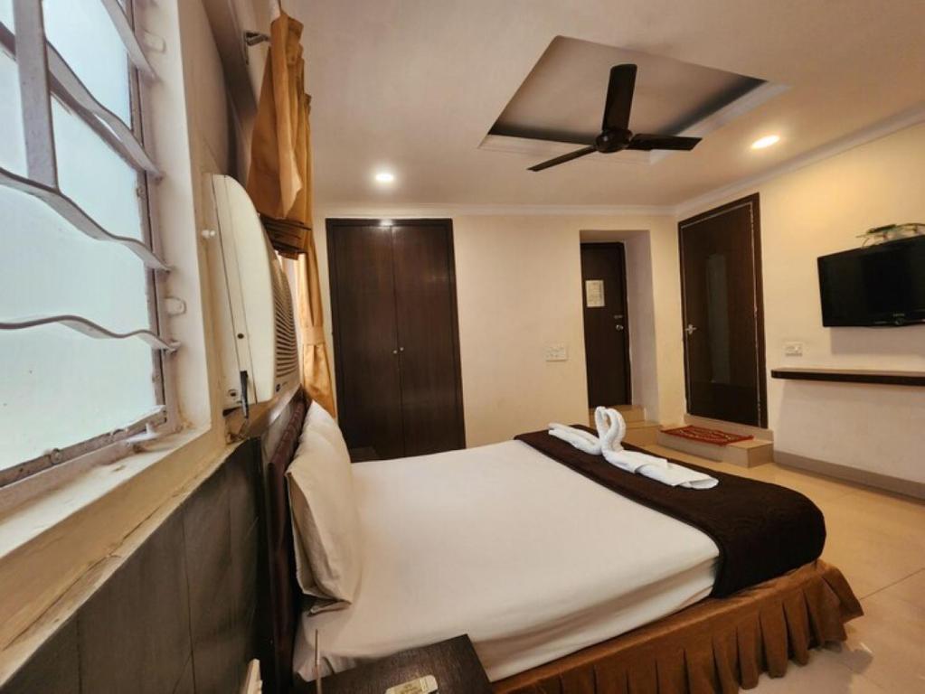 a bedroom with a large bed with a ceiling fan at Hotel Al Sana in Kolkata