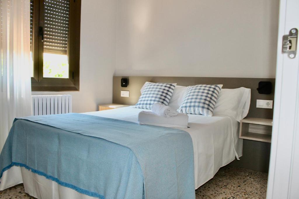 Cama con sábanas y almohadas azules y blancas en Crescen House, en pleno corazón de Rioja Alavesa, en Baños de Ebro
