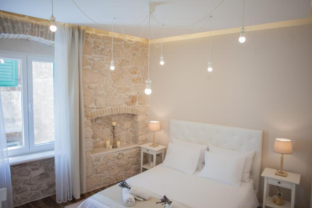 a bedroom with a white bed and a stone wall at Barone Room in Šibenik