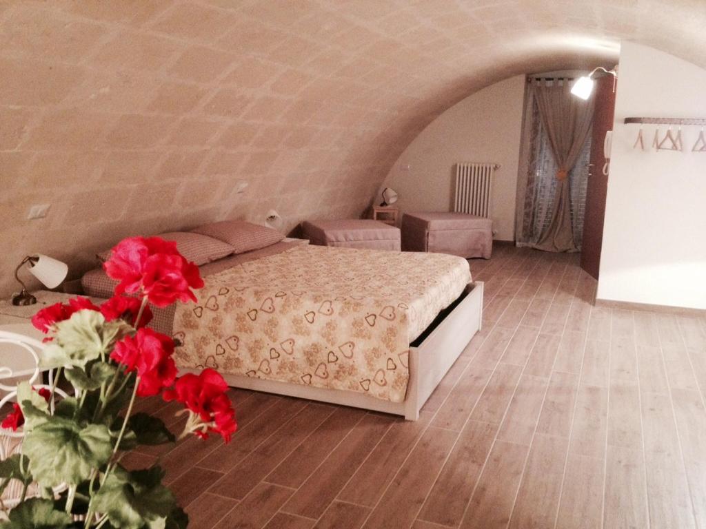 sypialnia z łóżkiem i czerwonymi kwiatami w pokoju w obiekcie Le due arcate w mieście Matera