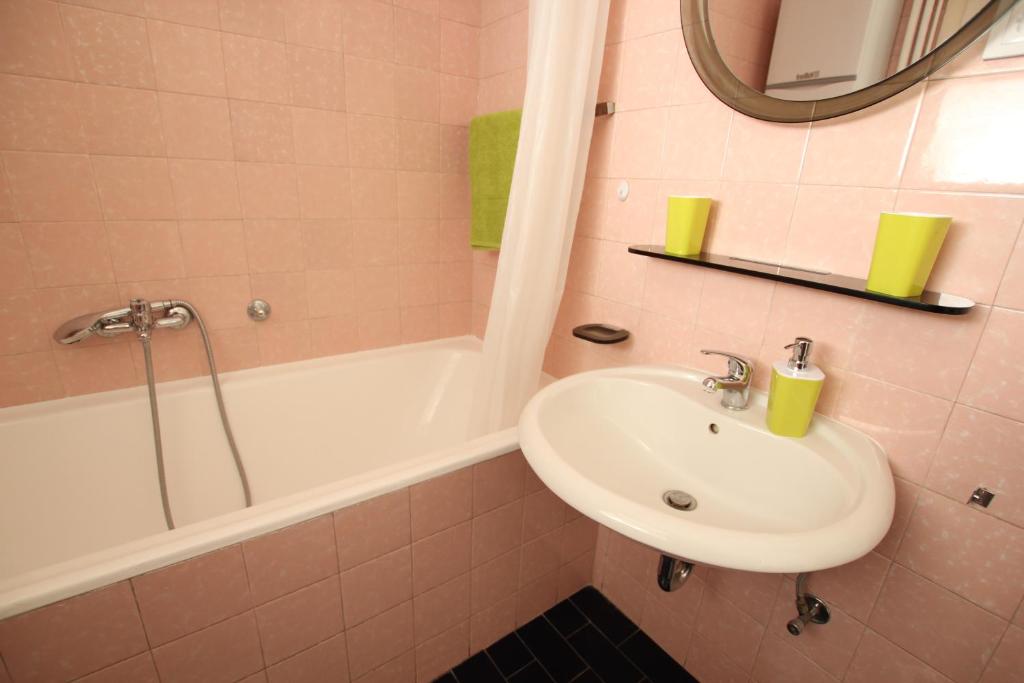 W łazience znajduje się umywalka oraz wanna z lustrem. w obiekcie Apartment Keglich w Zagrzebiu