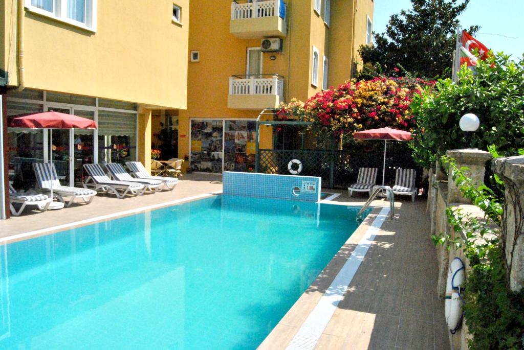 a swimming pool in front of a building with chairs and umbrellas at Benna Hotel in Antalya