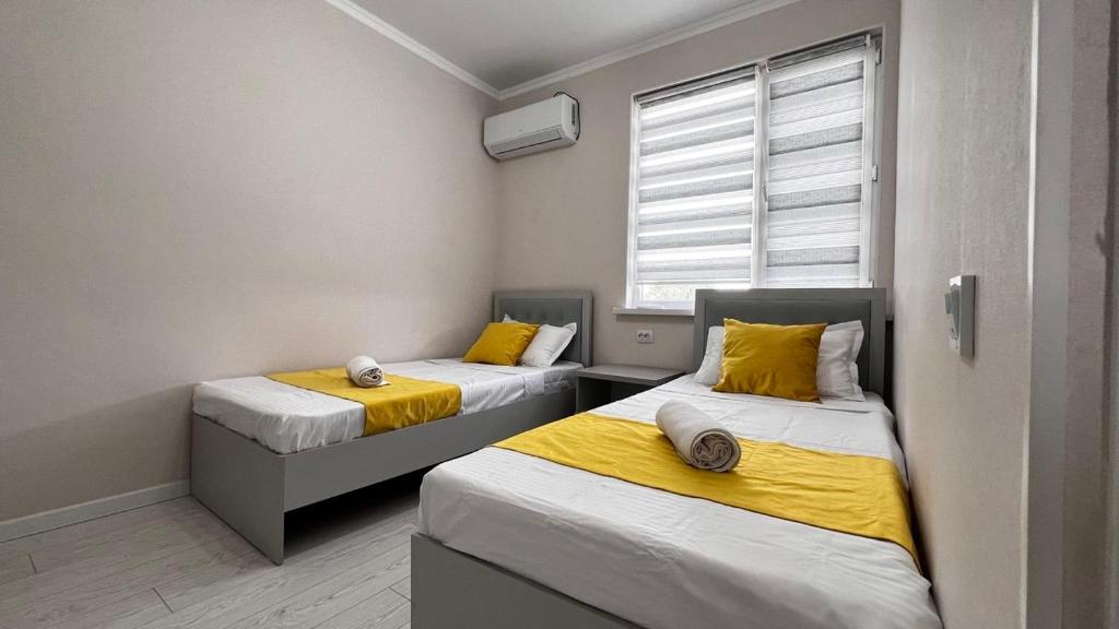 zwei Betten in einem kleinen Zimmer mit Fenster in der Unterkunft Comfort Point Hotel in Bischkek