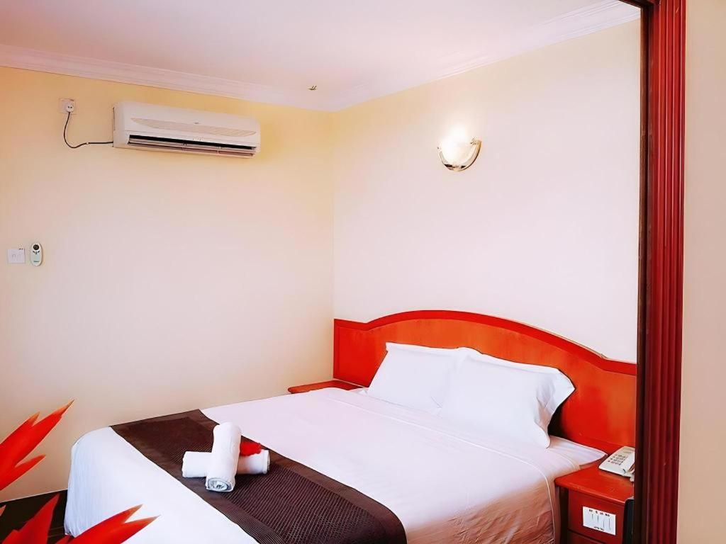 a bedroom with a white bed with a mirror at Global Hotel Labuan in Labuan