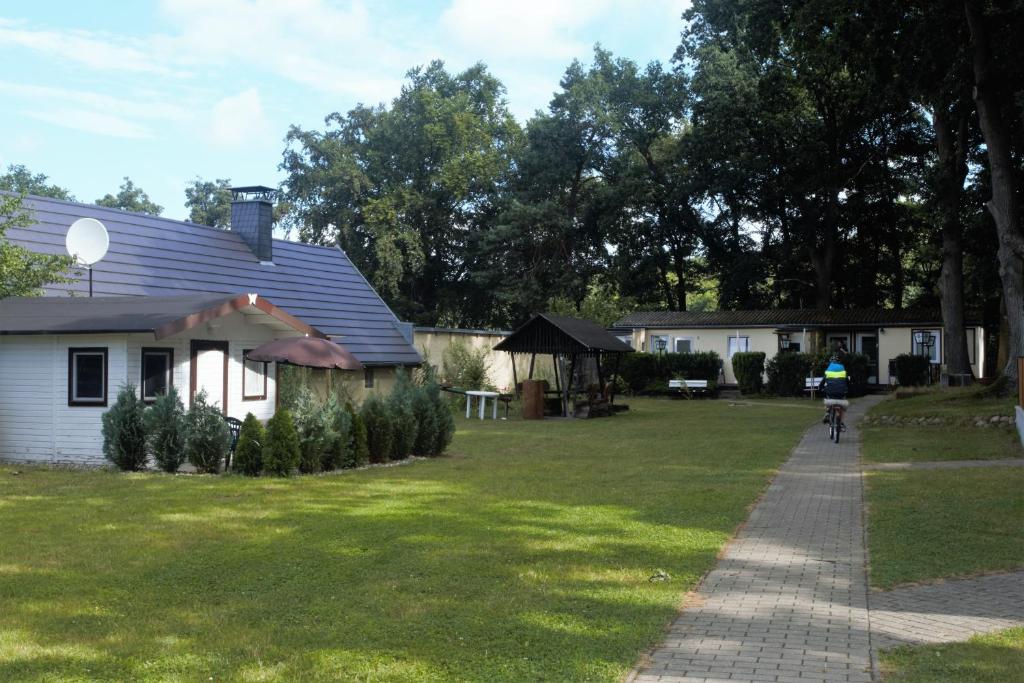 eine Person, die mit dem Fahrrad auf einem Bürgersteig neben einem Haus fährt in der Unterkunft Usedomer Bungalows in Korswandt