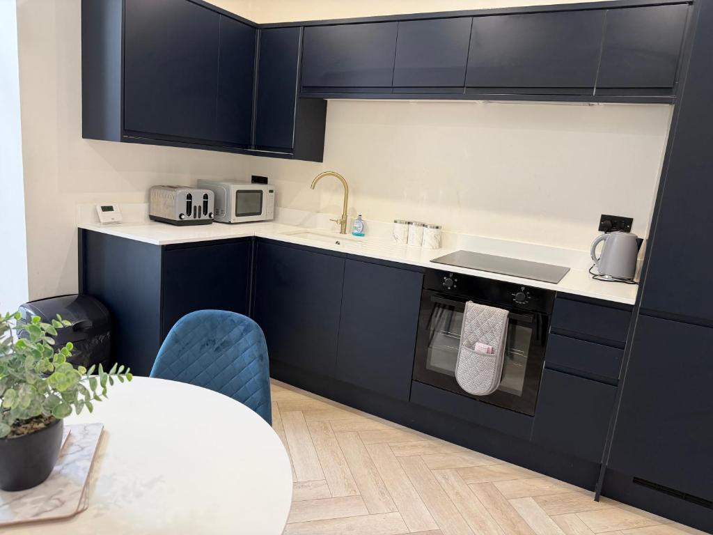 a kitchen with blue cabinets and a table and a sink at The Townhouse Collection 2BR Close To City Centre in Cardiff
