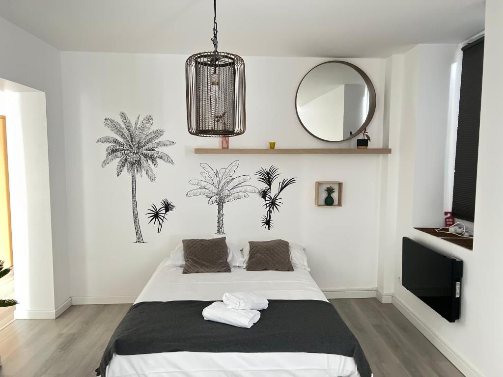 Saint-Julien-lès-MetzにあるAppartement 5 lits Wifi Un Séjour à Partの鏡付きのベッドと壁にヤシの木が飾られた寝室