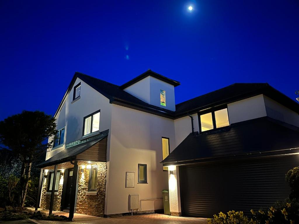 a white house at night with the moon in the sky at Stunning Beach House Indoor Pool in Portsmouth