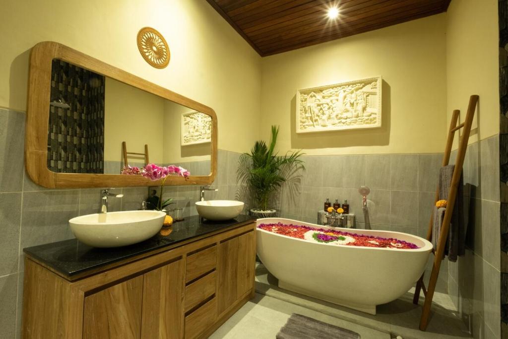 bagno con 2 lavandini, vasca e specchio di Rama Ubud Villa ad Ubud