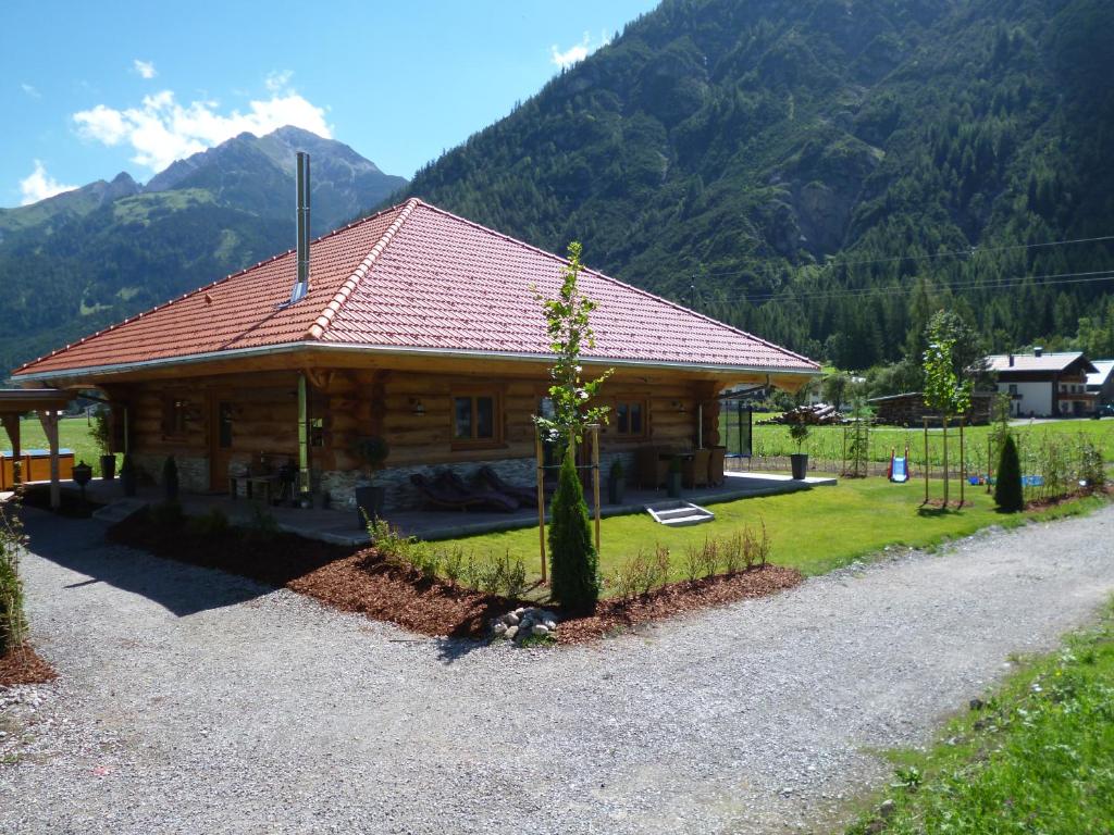 ein Blockhaus mit Bergen im Hintergrund in der Unterkunft Adlernest Lechtal in Bach