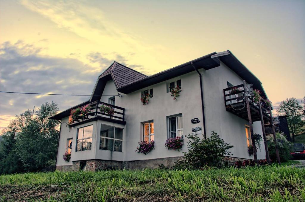 a white house with flower boxes on the windows at Romanówka in Ołdrzychowice Kłodzkie