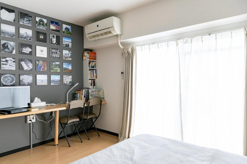 Schlafzimmer mit einem Schreibtisch, einem Computer und einem Fenster in der Unterkunft Hotel Small World in Hiroshima
