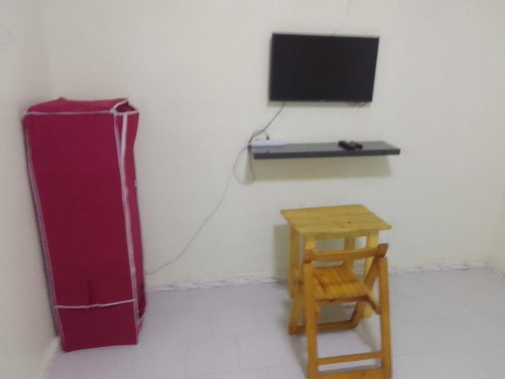 une pièce avec un réfrigérateur rouge et un tabouret en bois dans l'établissement Accueil Kounoune, à Kounoun