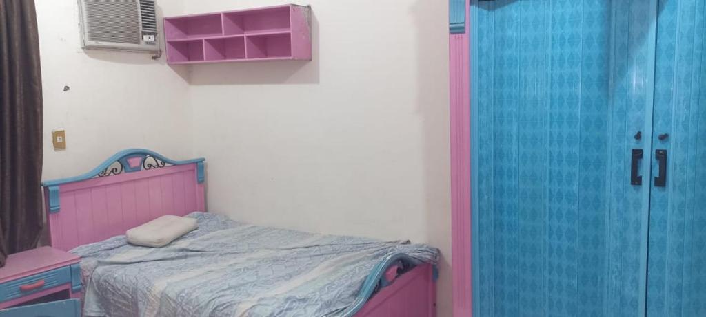 a bedroom with a pink bed and a blue door at الزقازيق فلل الجامعه برج رويال بلازا in Kafr az Zand