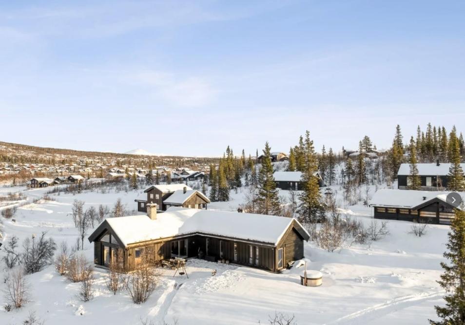 a house covered in snow in a snowy field at Moderne storhytte med 5 soverom og 3 bad in Beitostøl