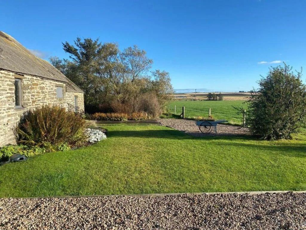 ein Hof mit einem Steinhaus und einer Bank in der Unterkunft Drumdry in Wick