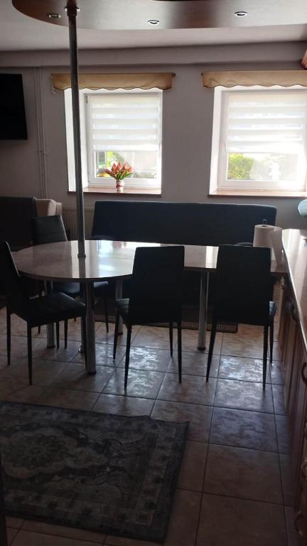 a dining room with a table and chairs and two windows at Dom Kopernika 4 in Chełm