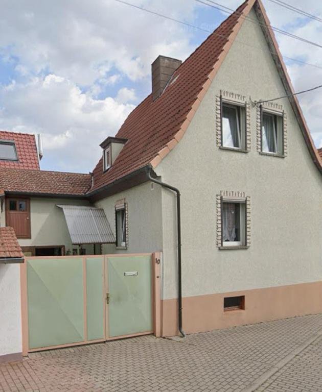 a white house with a gate and a roof at Ferienhaus WorkersParadise in Elxleben