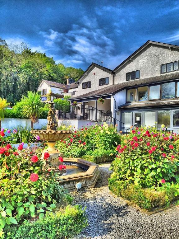 a large house with a fountain in a garden at Damson Dene Hotel in Bowness-on-Windermere