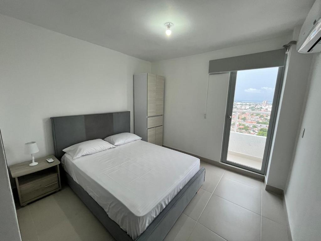 a white bedroom with a bed and a large window at New Sea View Torre 811 in Cartagena de Indias