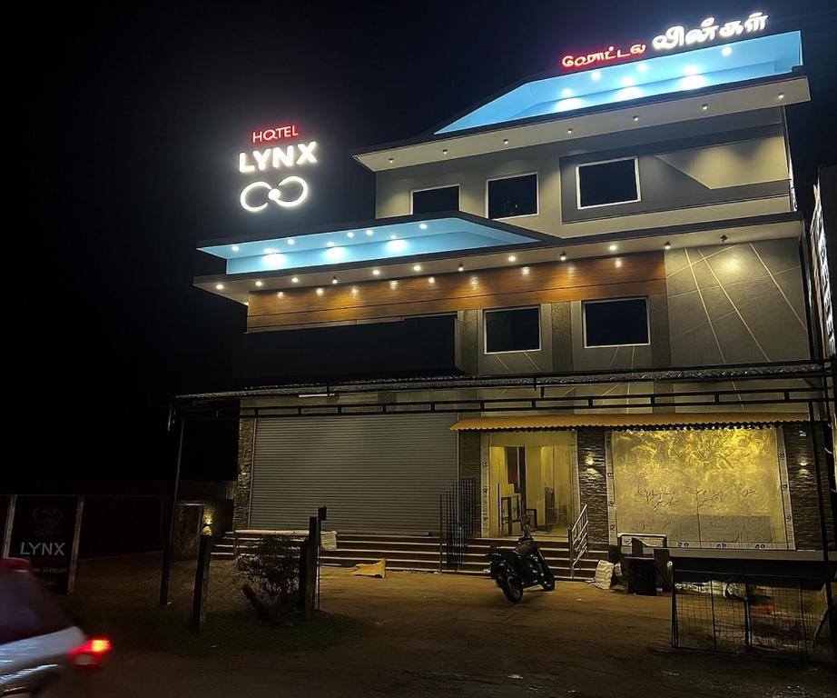 a building with a motorcycle parked in front of it at Hotel Lynx in Kumbakonam