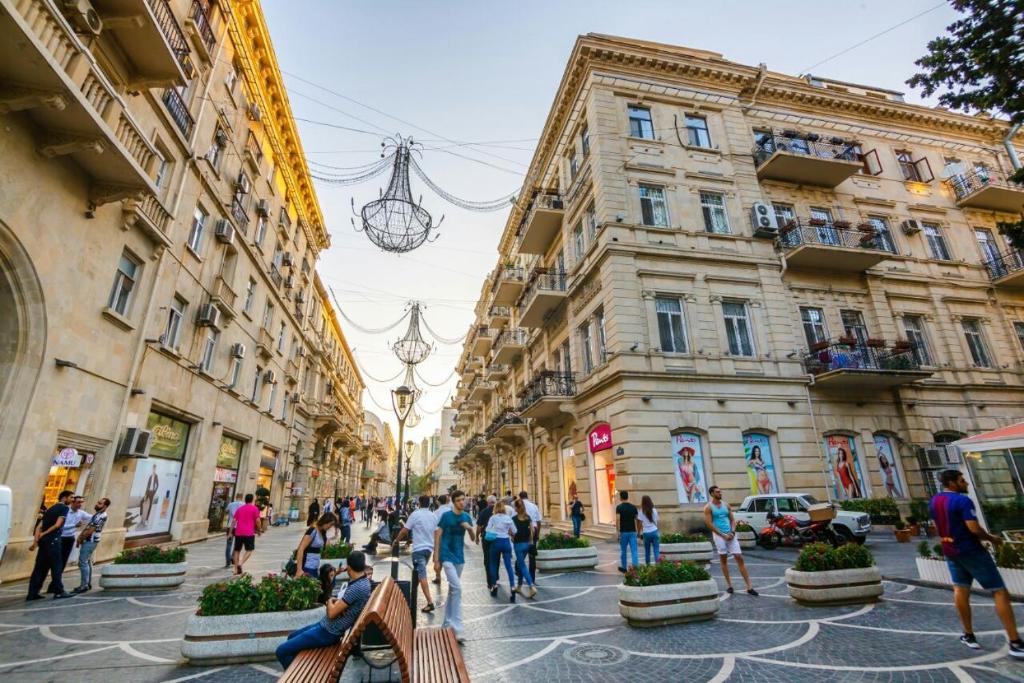 バクーにあるNIZAMI STREET ViP PRESTIGE APARTMENTの建物が並ぶ通りを歩く人々のグループ