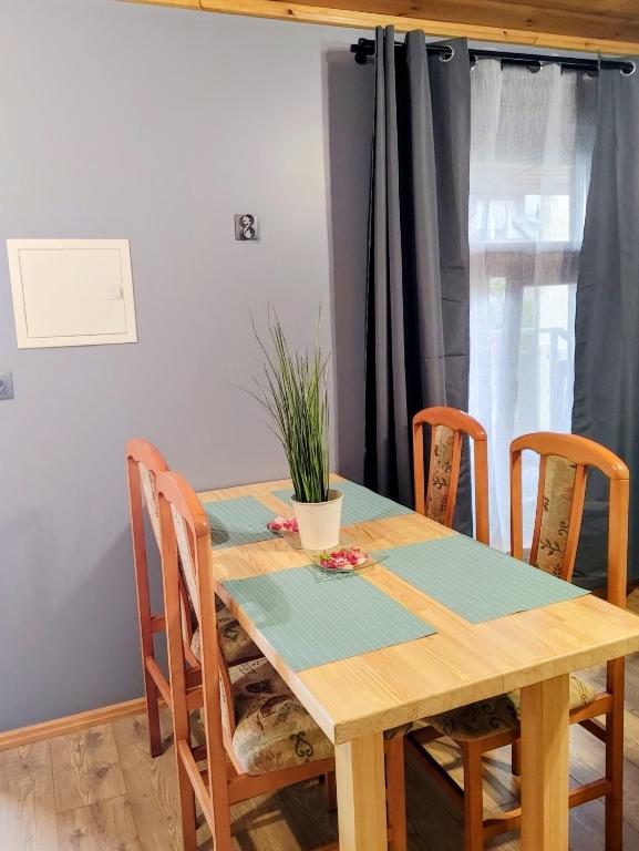a wooden table with chairs and a plant on it at Apartamenty Jodłowa in Suwałki