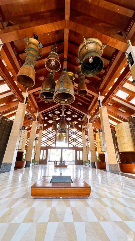 A tall interior hall displaying many bells beneath a wood-beamed roof.