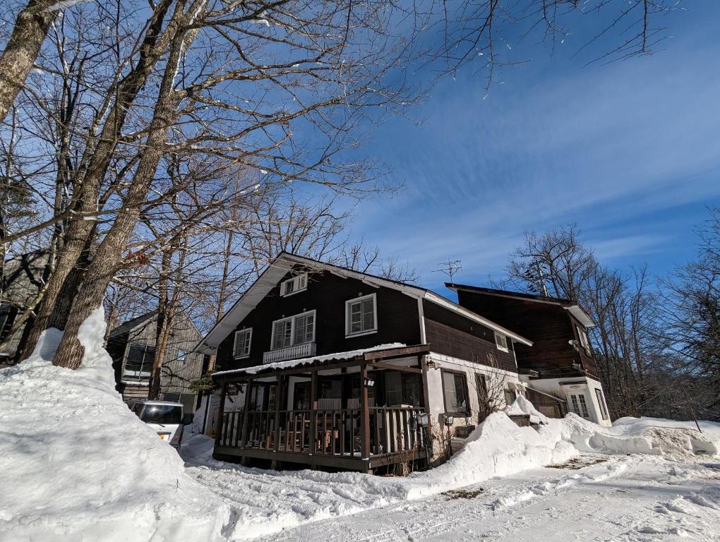 a house with snow on the ground in front of it at Sugi Lodge in Hakuba
