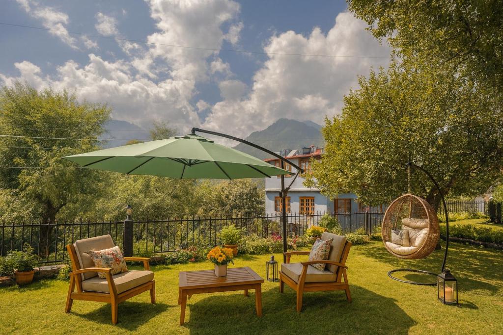 a patio with two chairs and a green umbrella at Sita Hotel & Cottage, Manali - A Boutique Wellness Hotel in Manāli