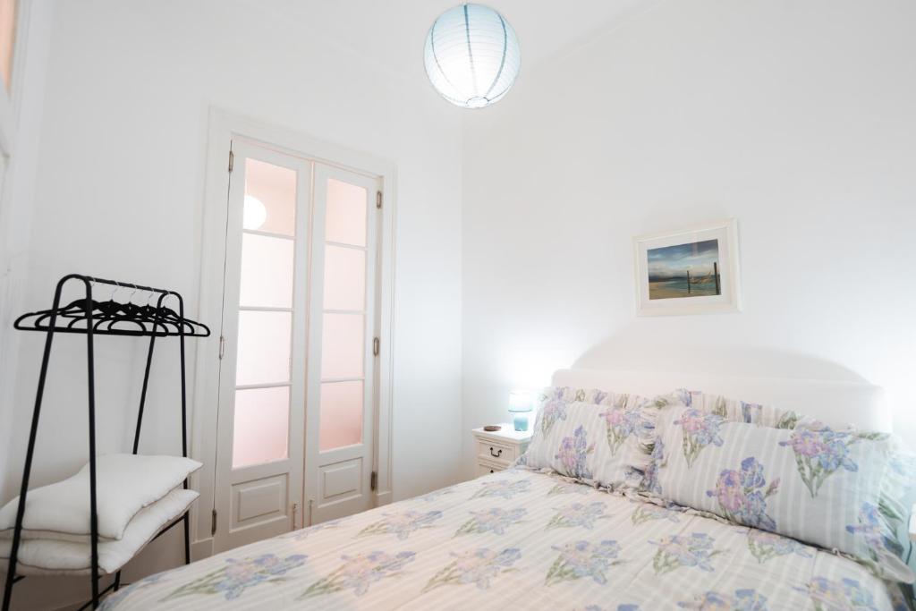 a white bedroom with a bed and a window at Alfarrobeira House in Cascais