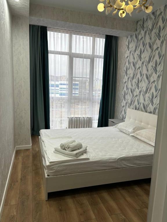 a bedroom with a bed with white sheets and a window at Prestige Ap in Ustʼ-Kamenogorsk