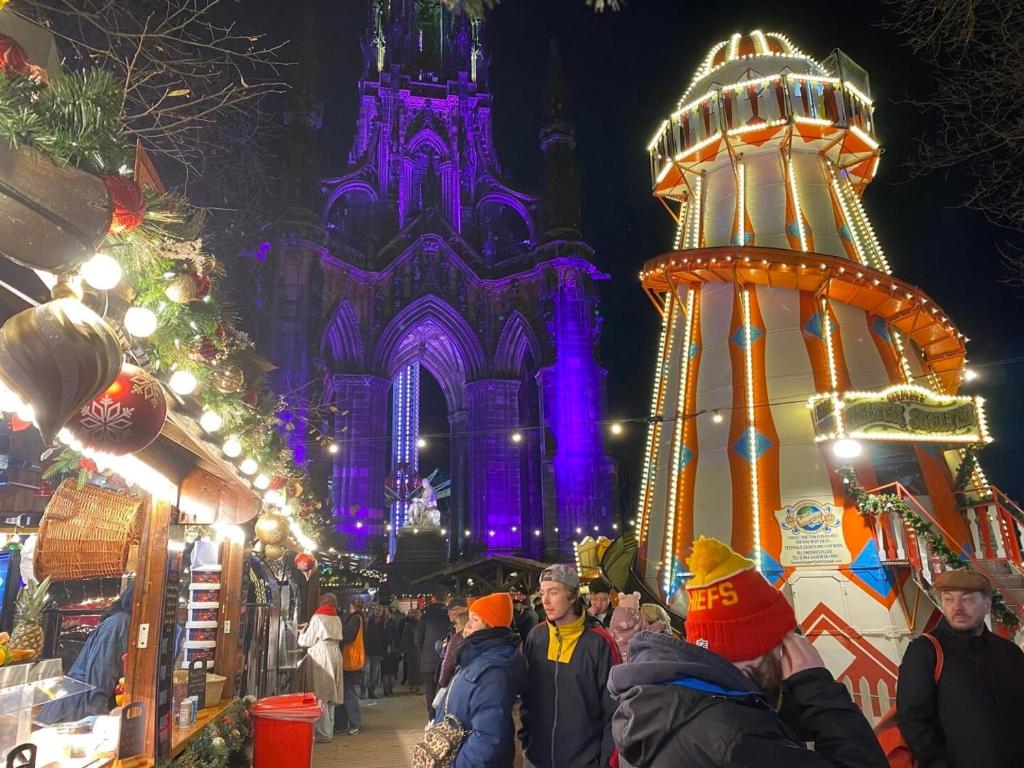 a group of people walking around a christmas market at night at Apart Bernard Rooms in Edinburgh
