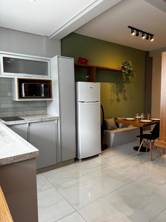 a kitchen with a white refrigerator and a table at Studio com Garagem, Térreo com Acesso privativo e WIFI, a 5 Minutos do Centro in Poços de Caldas