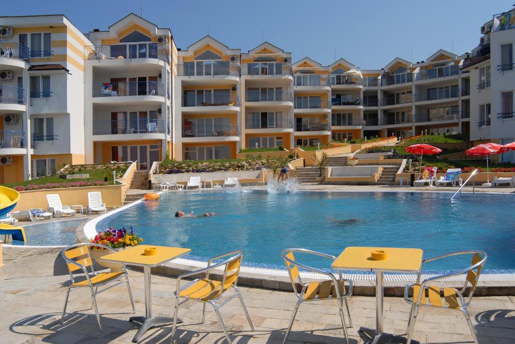 een zwembad met tafels en stoelen en appartementsgebouwen bij Apartments in Complex Panorama in Sozopol