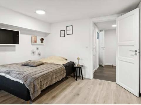 a white bedroom with a bed and a television at Østerbrogade 49 in Holstebro