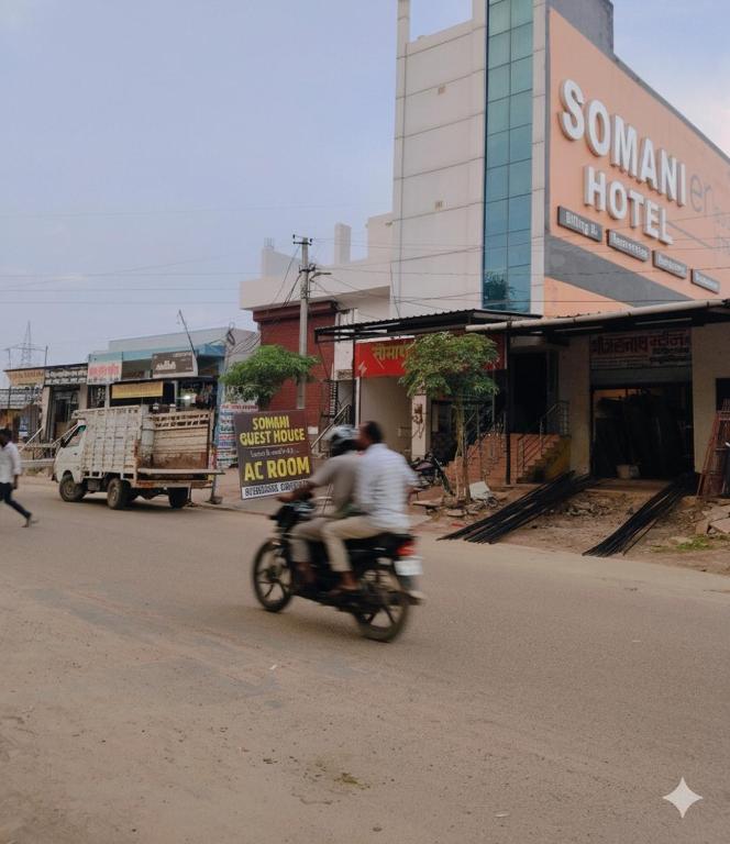 twee mensen die op een motor door een straat rijden bij Somani guest house in Bāsni