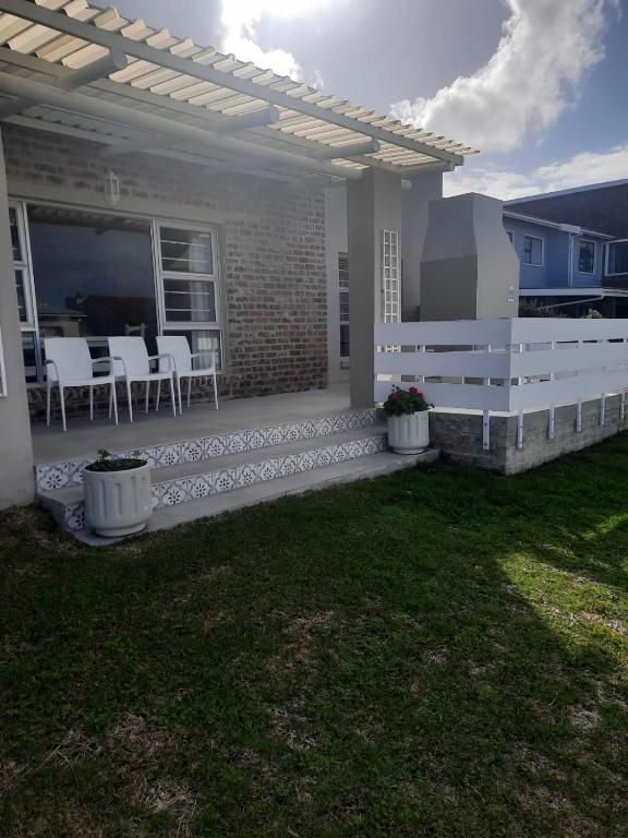 a patio with chairs and tables on a house at StruisPlace in Struisbaai
