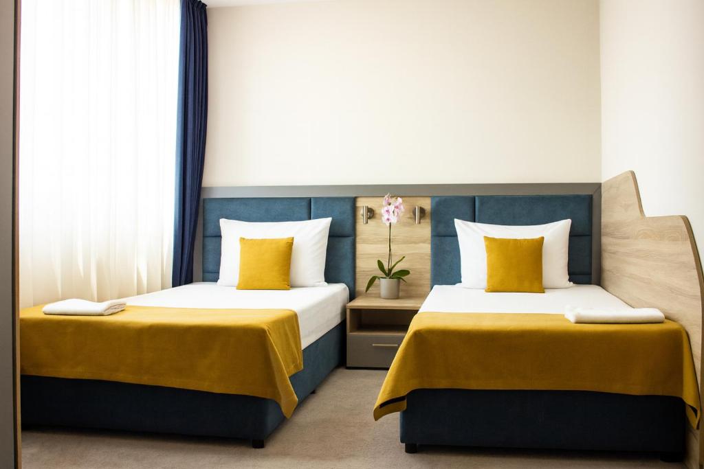 two beds in a room with yellow and blue at SPS Hotel in Plovdiv